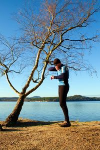 Man athlete checking time during workout run exercise outdoors at ocean beach in sunny cold morning.