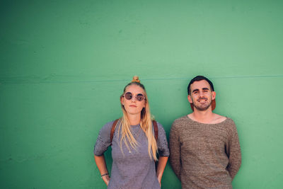 Portrait of smiling friends standing against green wall