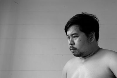 Portrait of young man looking away against wall