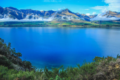 Scenic view of lake and mountains against blue sky