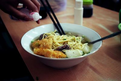 Midsection of person having noodle soup in bowl