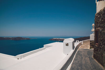 Building by blue sea against clear sky on sunny day