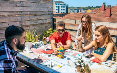 Group of friends playing with jenga game in rooftop on a summer party