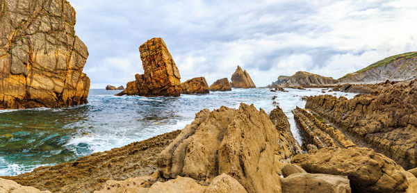Panoramic view of rocks on beach against sky