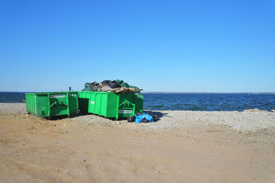 Deck chairs on beach against clear blue sky