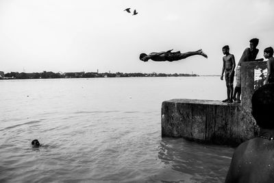 Man jumping on beach against clear sky