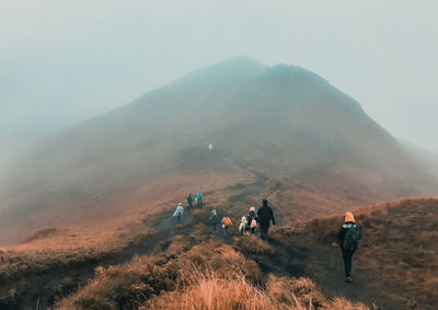 People walking on land against mountain range