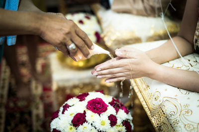 Cropped image of woman pouring water on bride hands during wedding ceremony
