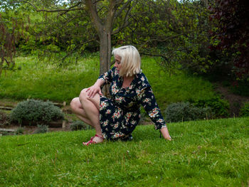 Mature woman sitting on grassy field in park