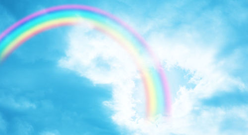 Low angle view of rainbow against blue sky