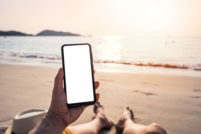 Midsection of man using mobile phone at beach