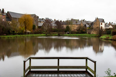 Buildings by lake against sky