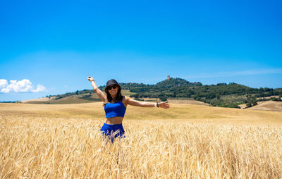 Girl walking through wheat fields in tuscany