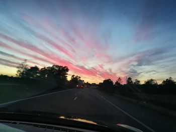 Cars on road against sky during sunset