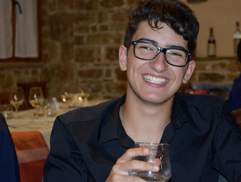 Portrait of smiling teenage boy drinking wine at home