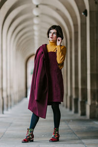 Full length of young woman standing against built structure