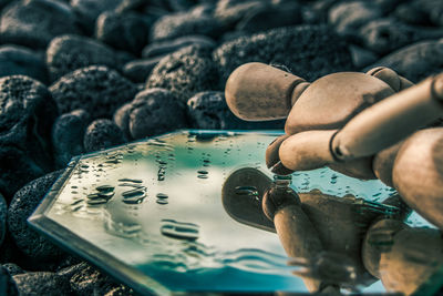 Close-up of wooden figuring on wet mirror