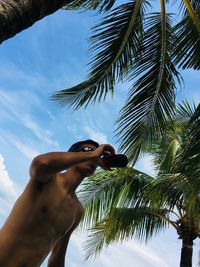 Low angle view of man drinking alcoholic drink bottle against cloudy sky