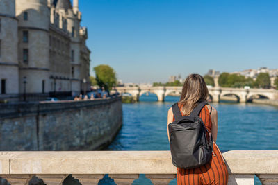 Rear view of woman standing on bridge over river against sky