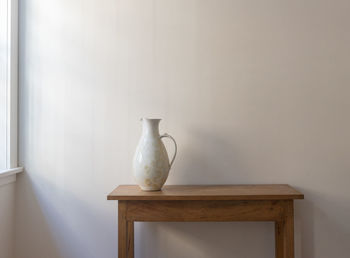 White vase on table against wall at home