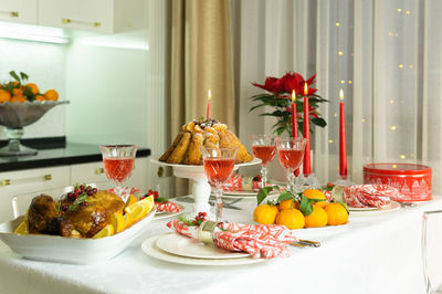 A festive table with baked chicken, tangerines, candles, cake and glasses of wine. holiday.