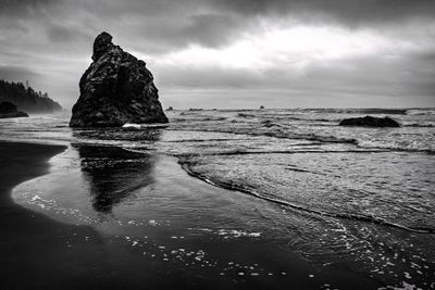 Rock formation on beach against sky