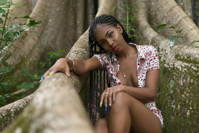 Portrait of woman sitting against tree trunk