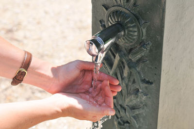 High angle view of woman with hands cupped below drinking fountain