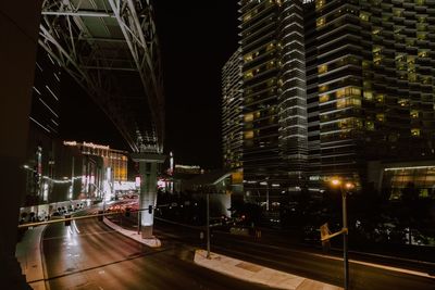 Illuminated street amidst buildings in city at night