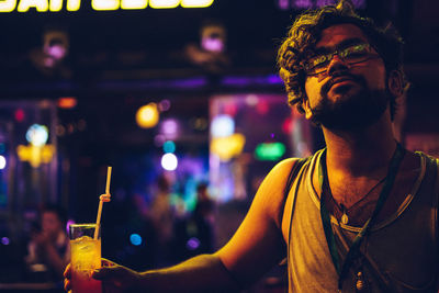 Full length of young man drinking glass at night