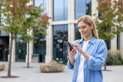 Young woman using mobile phone in city