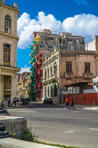 Road by buildings in city against sky