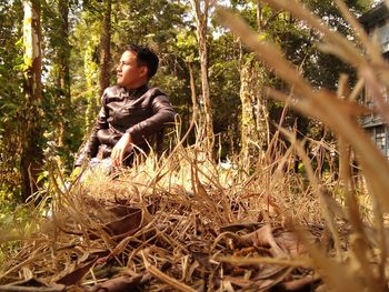 Full length of boy sitting in forest