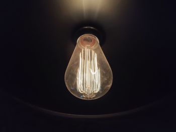 Low angle view of illuminated light bulb against black background