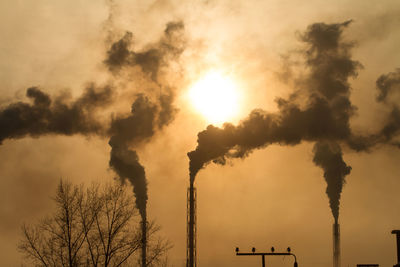 Smoke emitting from chimney against sky at sunset