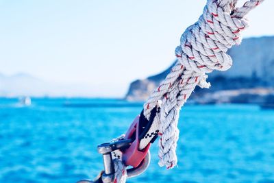 Close-up of rope tied to sea against sky