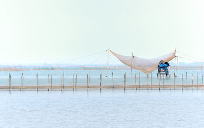 People fishing in sea against clear sky