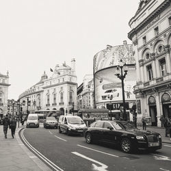 Cars on street in city against sky