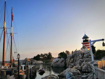 Sailboats moored at harbor against clear sky during sunset