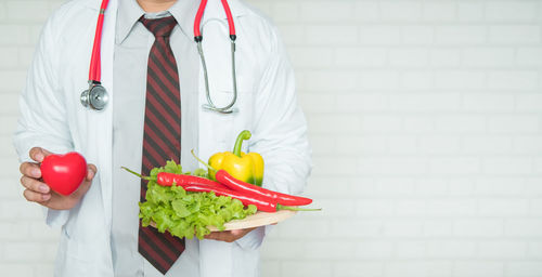 Midsection of doctor holding vegetables