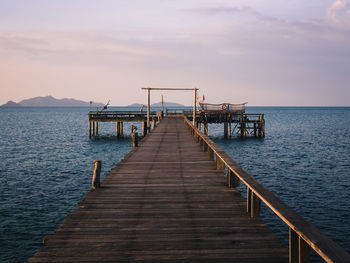 Scenic view of peaceful long wooden pier over blue water in sunset. koh mak island, trat, thailand.