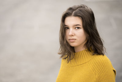 Teen girl in a yellow sweater with a smartphone