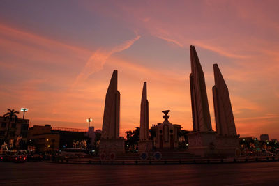 Silhouette of city against cloudy sky during sunset