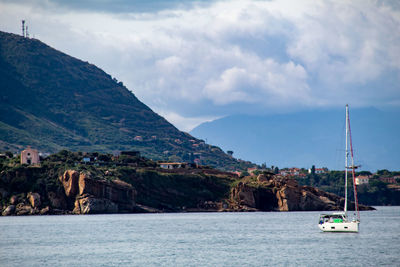 Sailboat on sea by buildings against sky