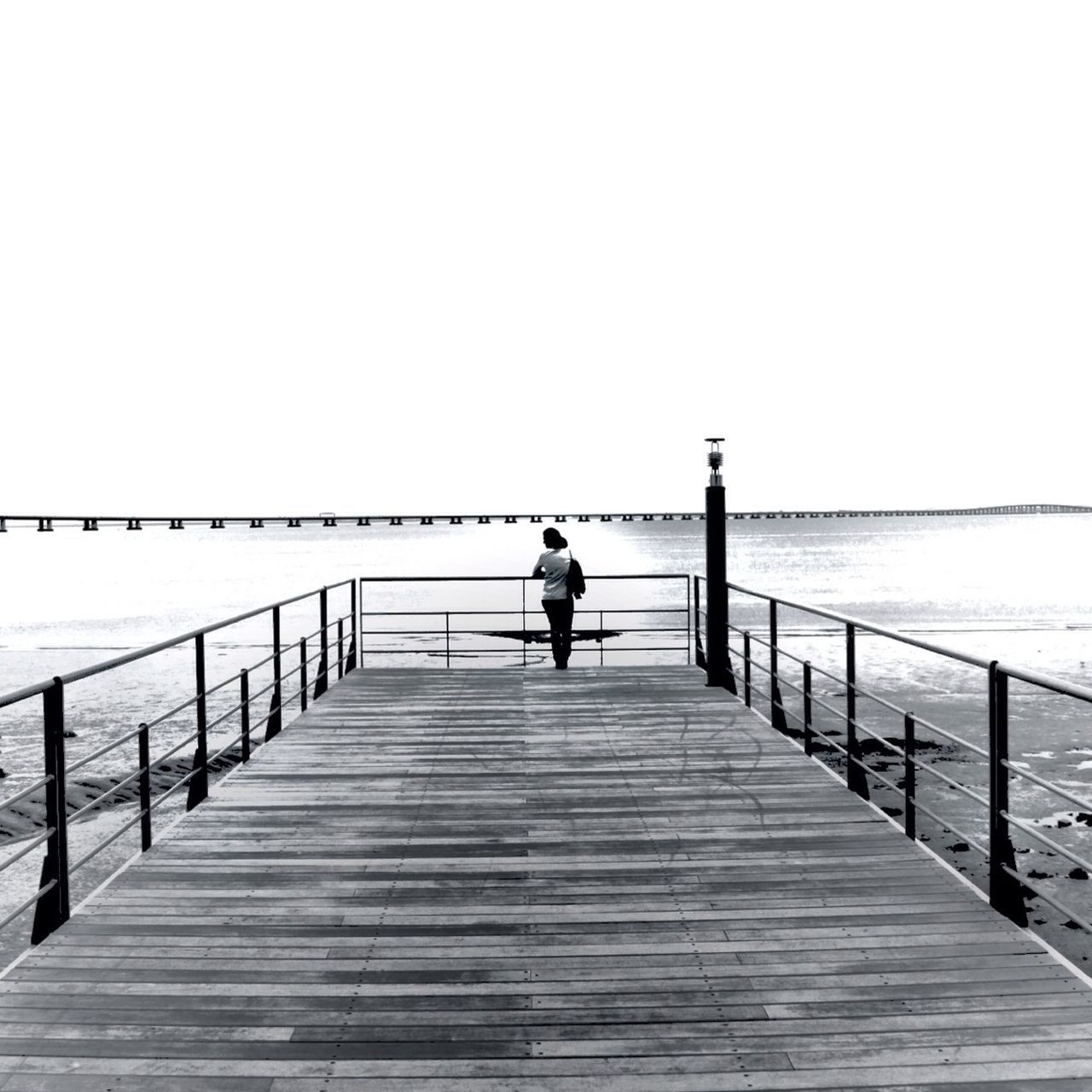 sea, pier, railing, water, the way forward, clear sky, copy space, rear view, full length, horizon over water, men, lifestyles, walking, tranquility, leisure activity, tranquil scene, jetty, nature