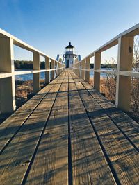 Footbridge over sea by buildings against clear sky