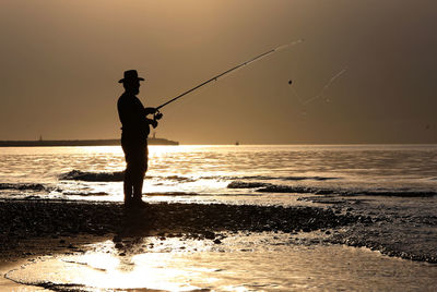 Silhouette man fishing in sea