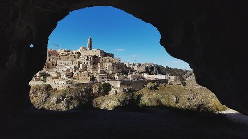 Buildings against sky seen through cave