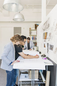 Colleagues working on blueprints in office