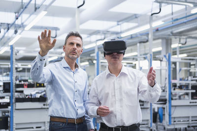 Two managers standing in company, using vr goggles